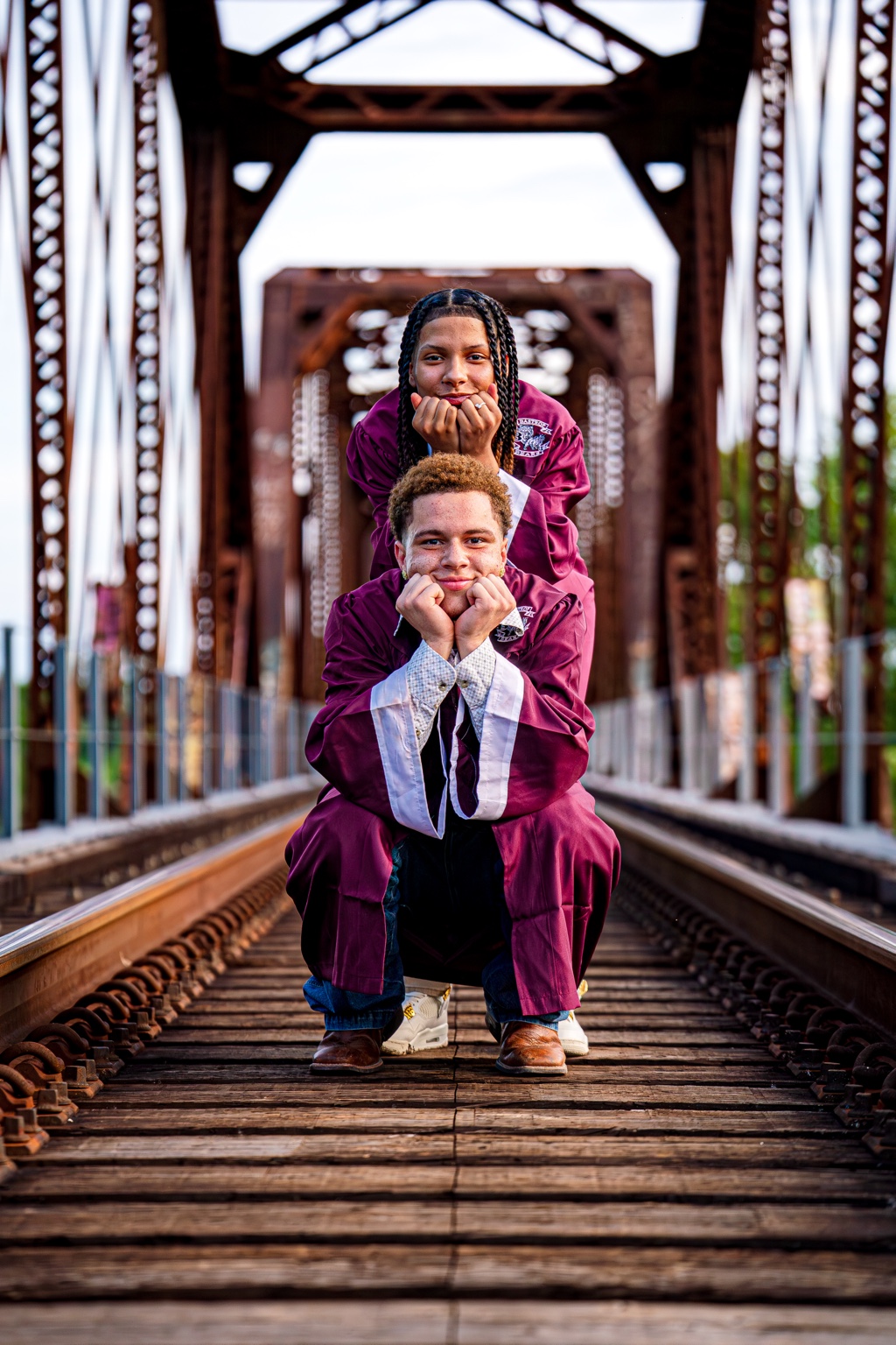 Two graduates posing together on a steel bridge