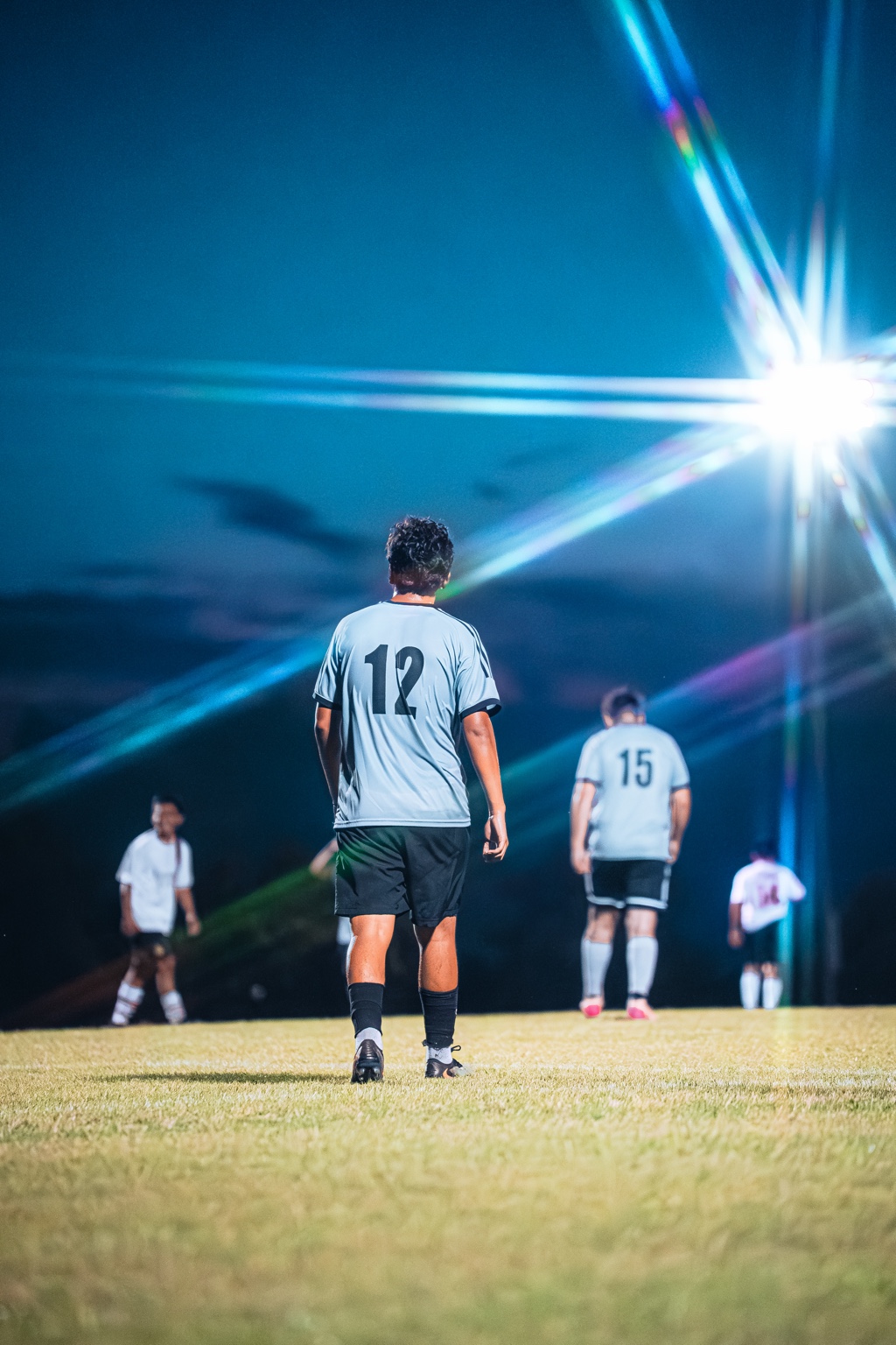 Soccer players on a field beneath bright stadium lights