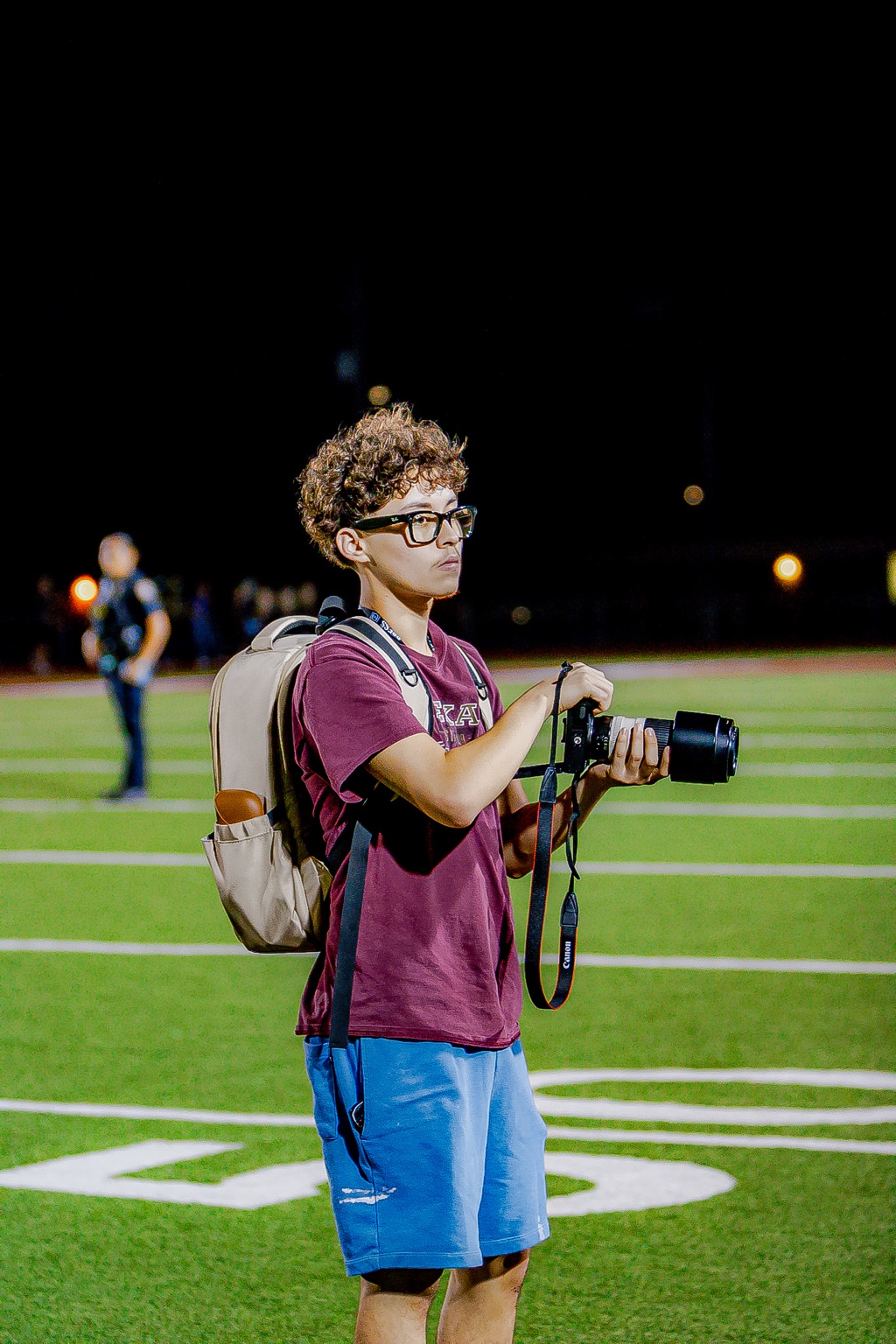Angel in a red shirt holding his camera on a sports field