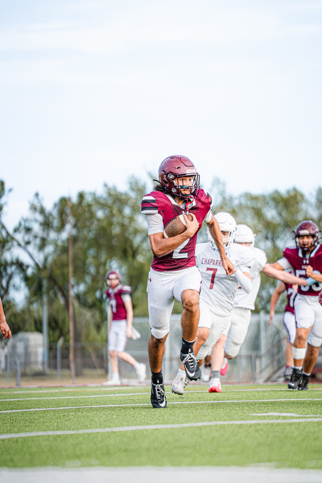 Football player running with the ball as players follow behind