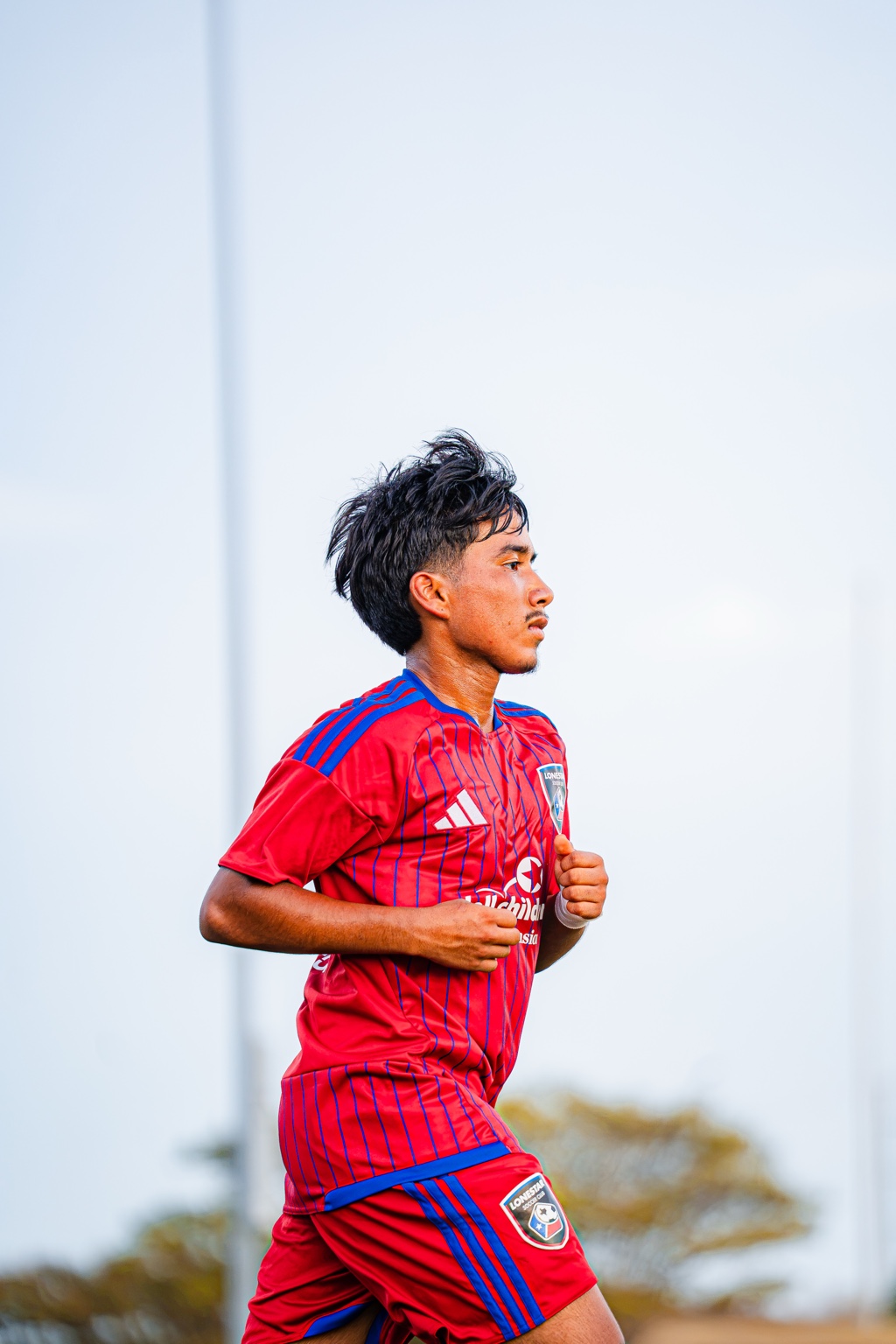 Soccer player in a red and blue uniform jogging on the field